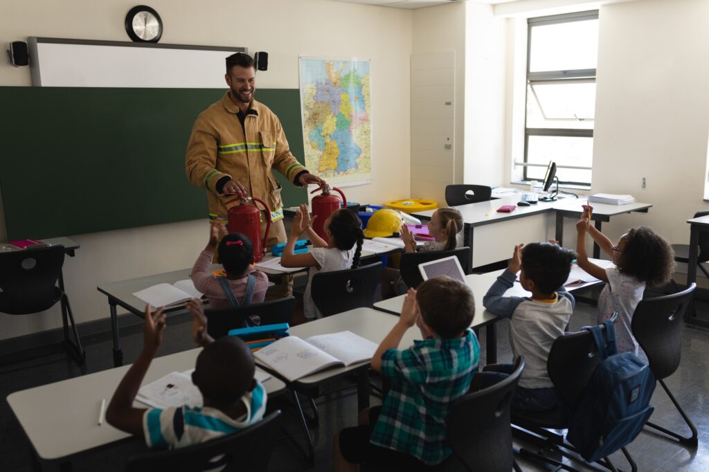 Schoolkids applauding firefighter in classroom